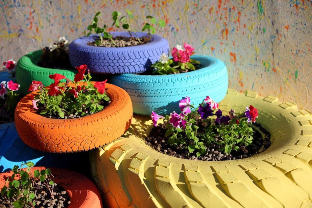 Flores plantadas em pneus reciclados e pintados com tinta de diversas cores, um exemplo de prática de design sustentável..