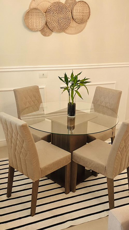 A imagem ilustra uma sala de estar com uma mesa com 4 cadeiras e nela há uma cor de parede para sala bege claro.