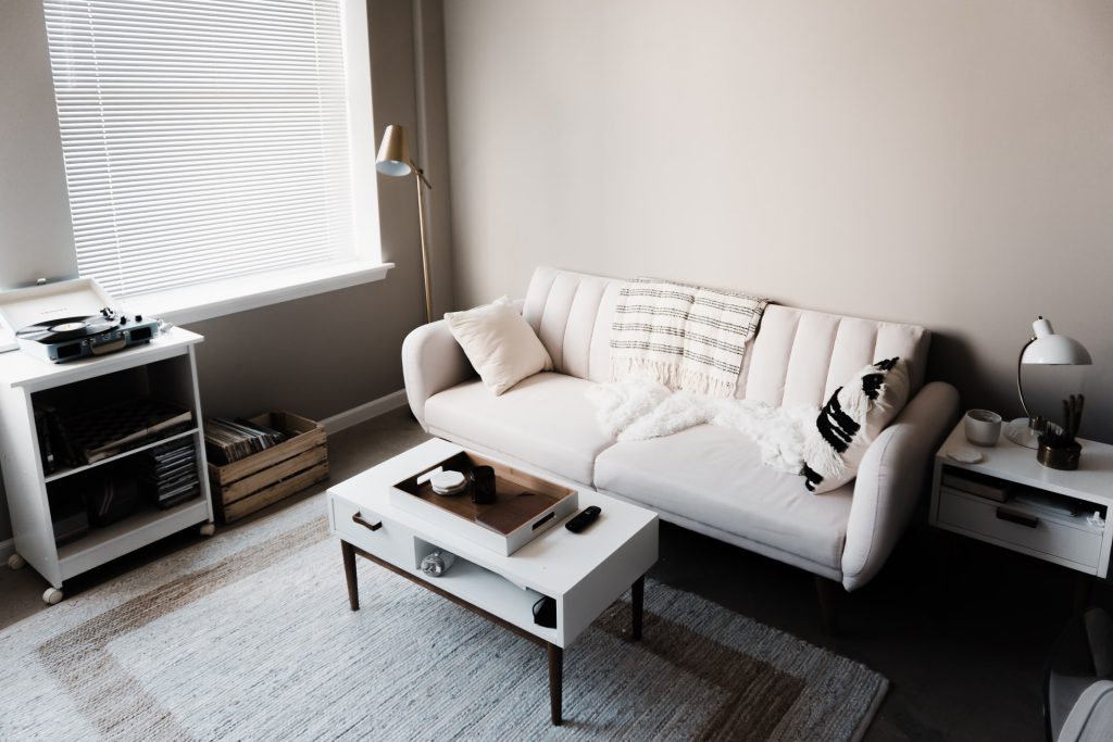 Sala de um apartamento pequeno decorada com sofá e mesa de centro brancos.