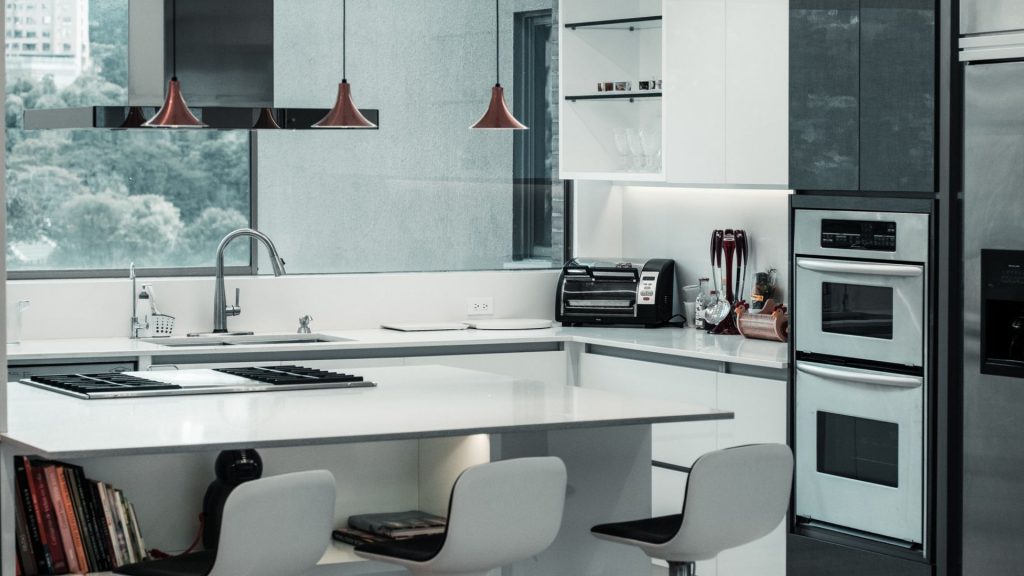 Cozinha com móveis brancos e em tons de cinza escuro e decoração clean, um exemplo de estilo contemporâneo.