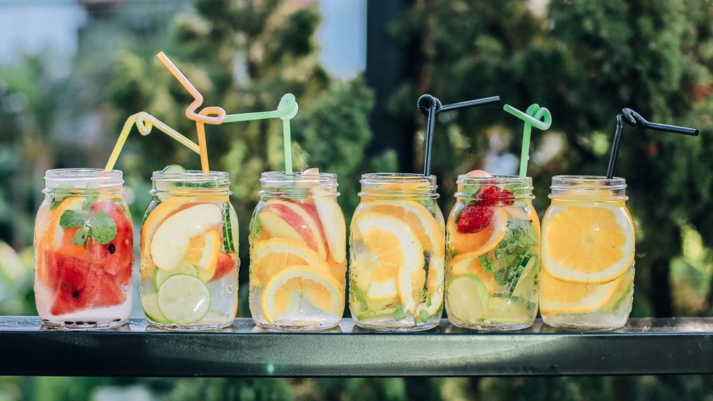 A imagem mostra seis canecas de vidro com bebidas e frutas, exemplificando o home bar.