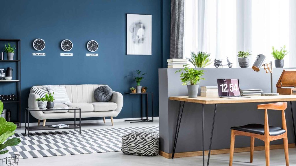 Sala com paredes azul e sofá branco com um canto para home office.