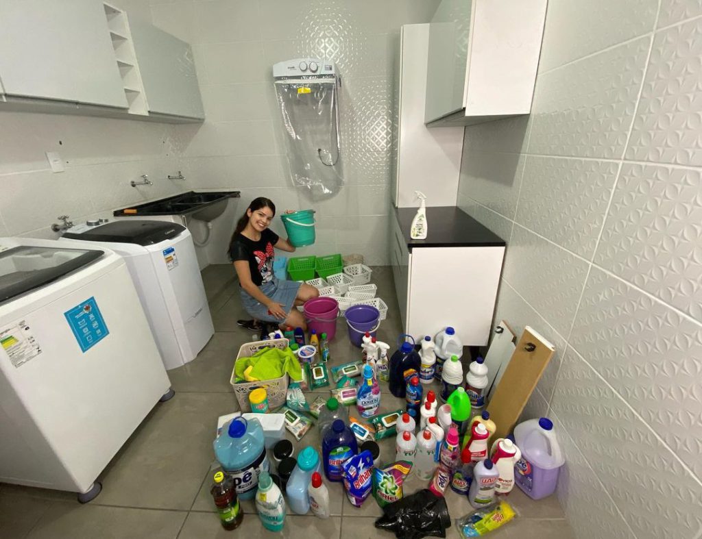 Cliente Madesa em sua lavanderia com vários produtos de limpeza no chão.
