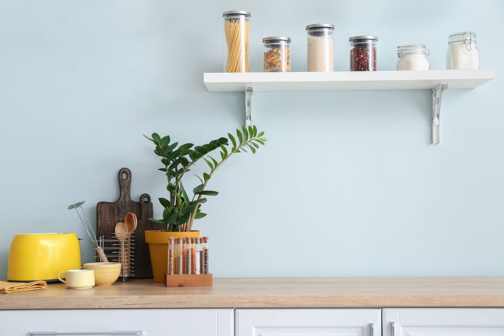 Foto de itens decorativos, utensílios e temperos em cima de um balcão de cozinha em frente a uma parede azul.