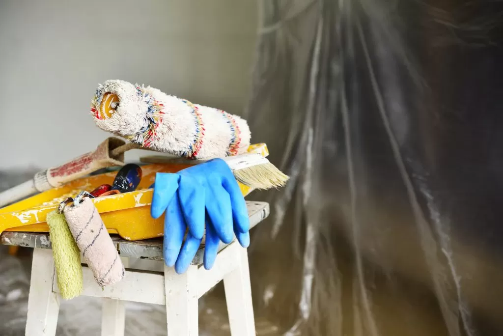 materiais para pintar uma parede, rolos de tinta, luvas, bandeja de tinta