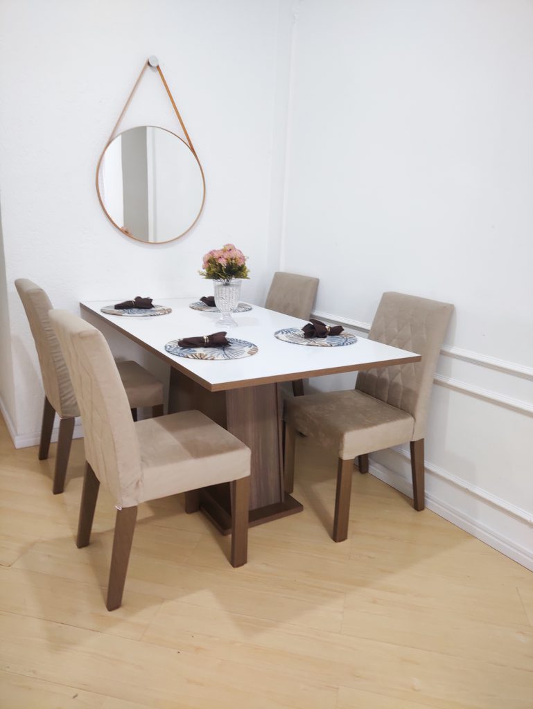 Mesa de jantar com tampo branco e com quatro cadeiras.