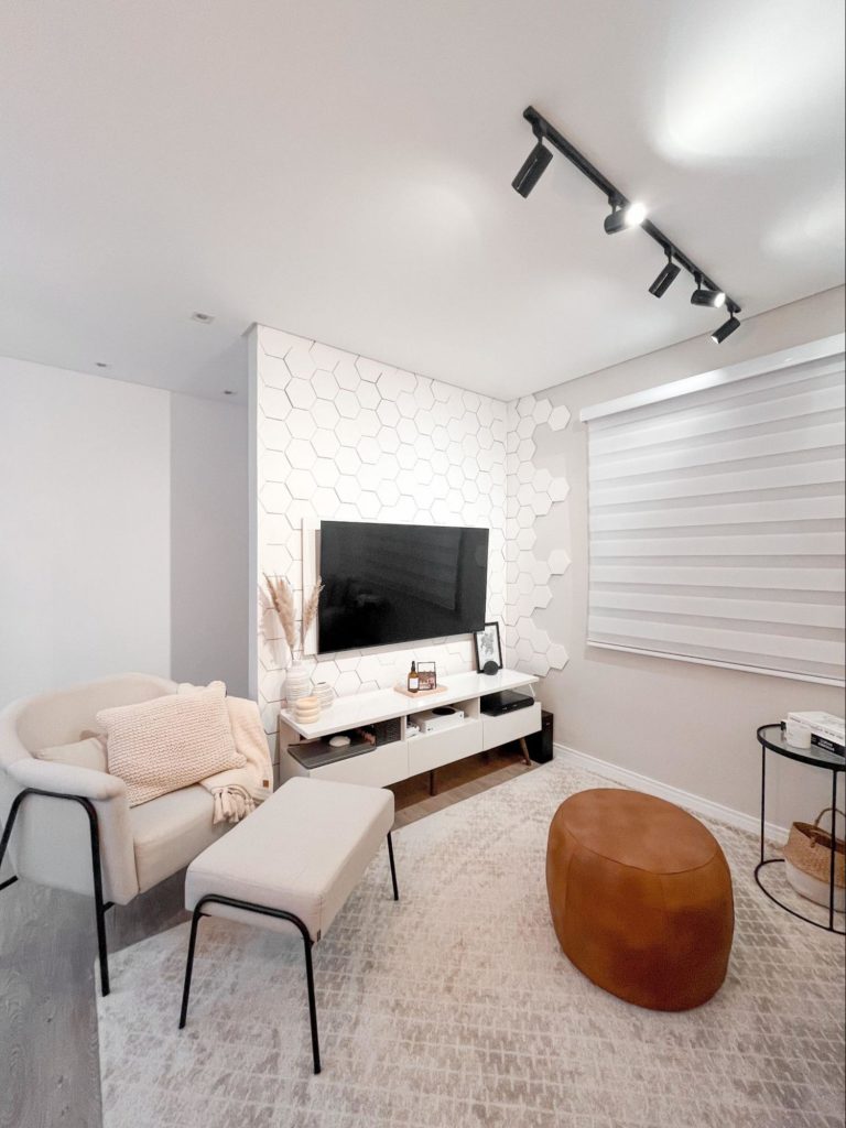 A imagem mostra uma sala de estar moderna com sofás brancos e uma tv grande.