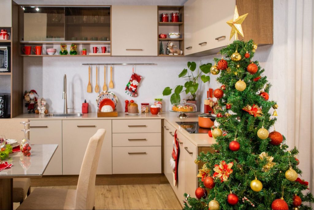 Cozinha Madesa, decorada com diversos utensílios natalinos nas cores verde e vermelho. À direita, uma árvore de Natal ao lado dos armários de cozinha.
