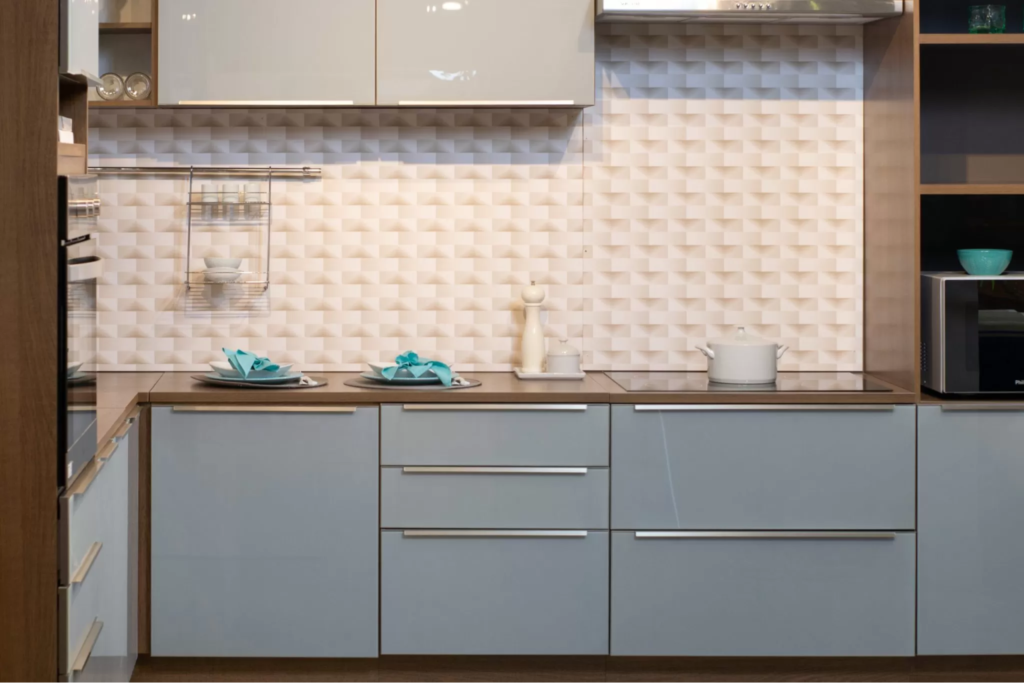 A imagem ilustra uma cozinha planejada de cor azul claro, com puxadores metálicos.