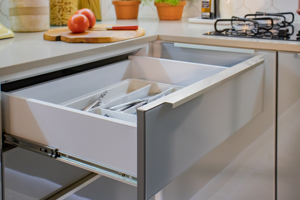 A imagem ilustra uma gaveta aberta com puxadores em metal, sendo um estilo de cozinha sofisticado.