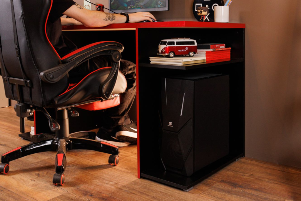 A imagem ilustra um garoto sentado em uma cadeira gamer em uma escrivaninha de madeira com detalhes vermelhos representando ideias para trabalhar em casa.