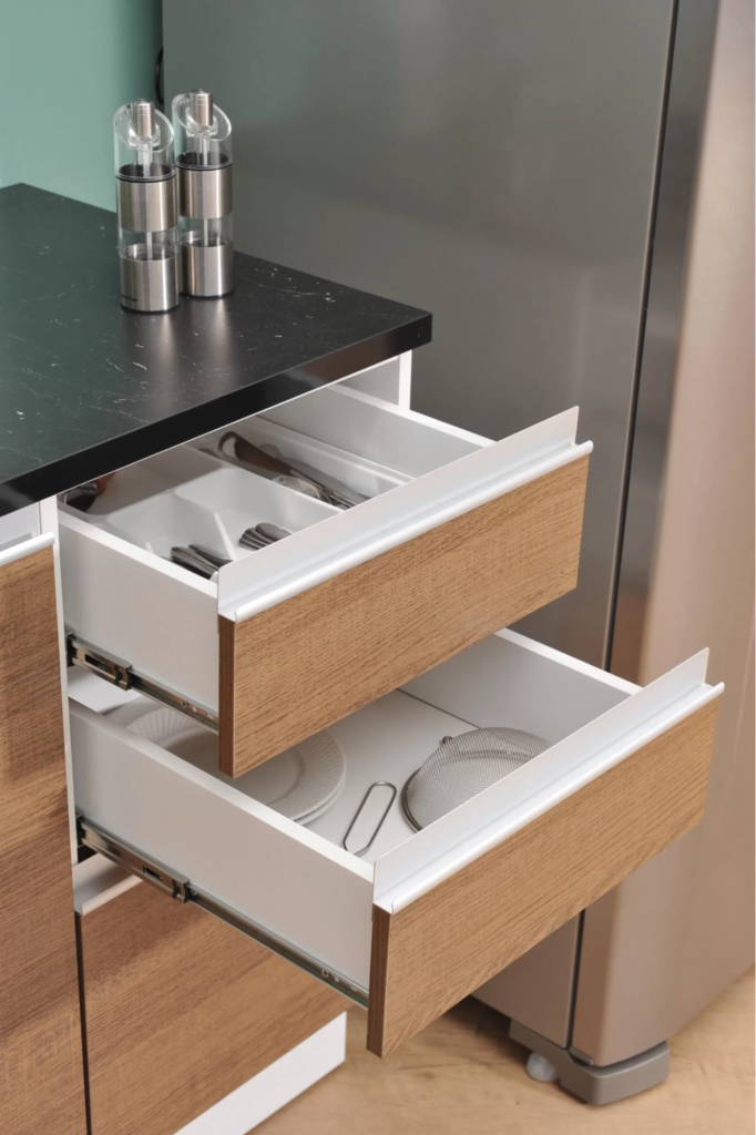 A imagem ilustra como organizar armário de cozinha através de uma bancada de madeira com 2 gavetas abertas.