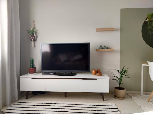 Sala de estar com rack Madesa na cor branca, decorado com alguns itens e plantas de forma minimalista. Na parede, prateleiras suspensas com mais decorações.