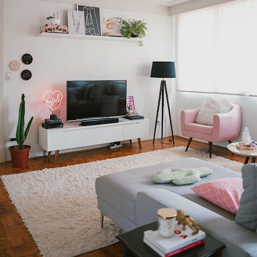 Sala de estar decorada em tons pastéis de rosa, branco e cinza. Com um rack Madesa branco e um sofá de um módulo, o espaço ficou super otimizado.