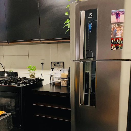 Balcão e armário aéreo Reims, na cor preta, decorados com utensílios de cozinha e eletrodomésticos.