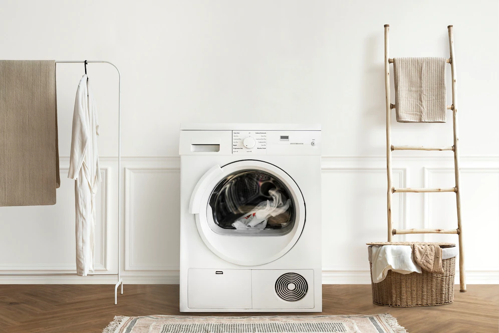 A imagem ilustra uma lavanderia moderna com uma máquina branca lava e seca.