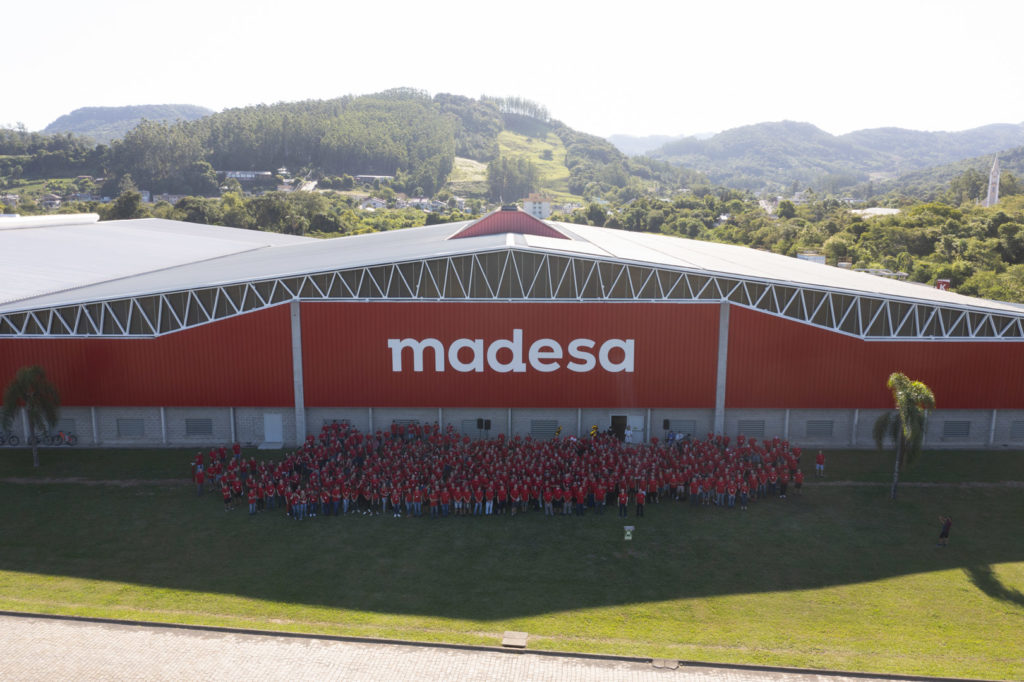 A imagem ilustra os colaboradores que ajudam a construir a cozinha dos sonhos Madesa. Usam todos roupas vermelha, combinando com a estética da indústria.