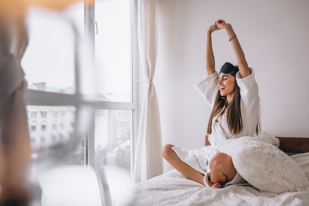 A imagem ilustra uma jovem mulher acordando em seu quarto branco após fazer a higiene do sono.