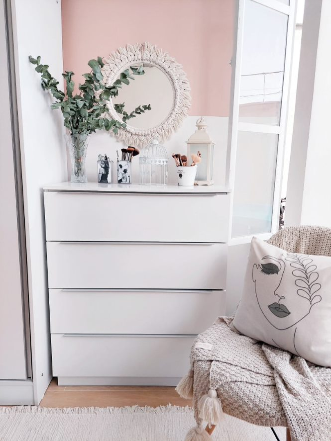 A imagem ilustra uma cômoda branca com espelho e detalhes decorativos em um quarto branco perfeito para a higiene do sono.