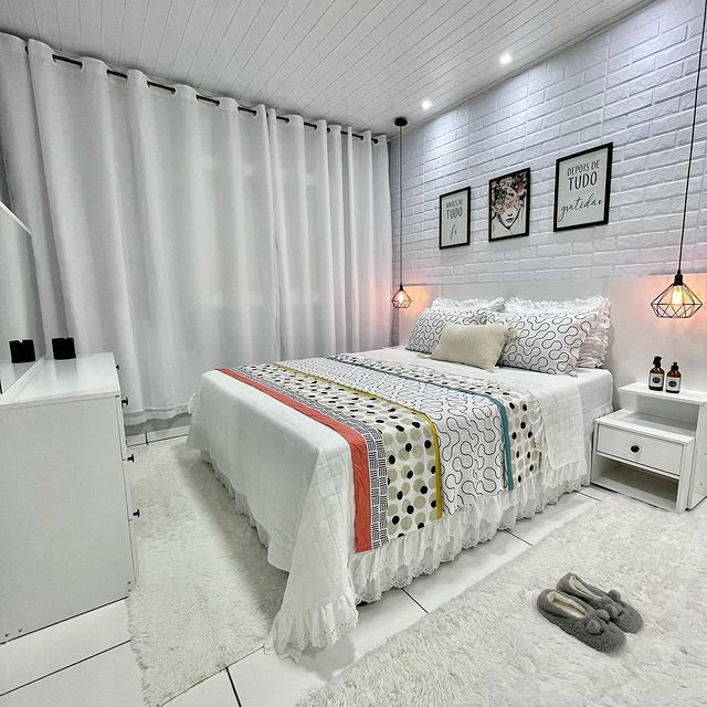A imagem ilustra um quarto branco com uma cama de casal, tapete e mesa de cabeceira brancas, criando um ambiente ideal para a higiene do sono.