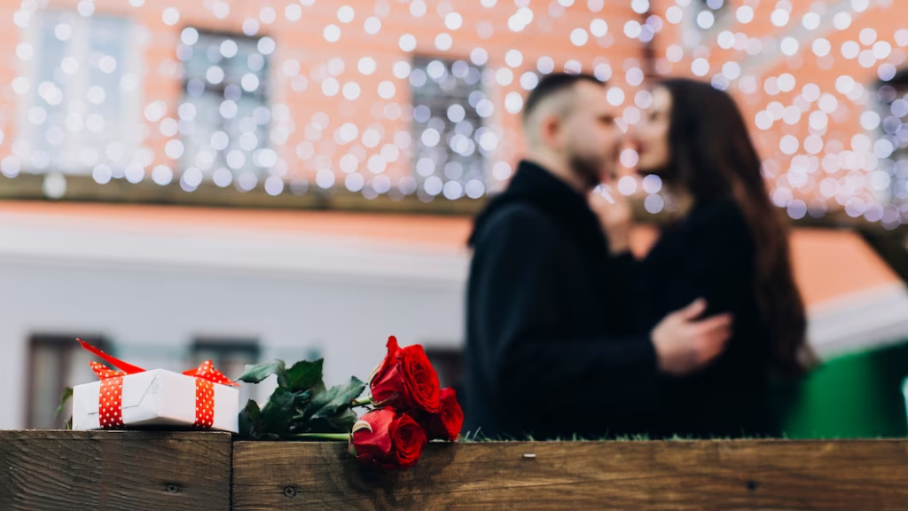 A imagem ilustra um casal se abraçando ao fundo e na frente um presente com um buque de rosas, simbolizando ideias para o dia dos namorados.