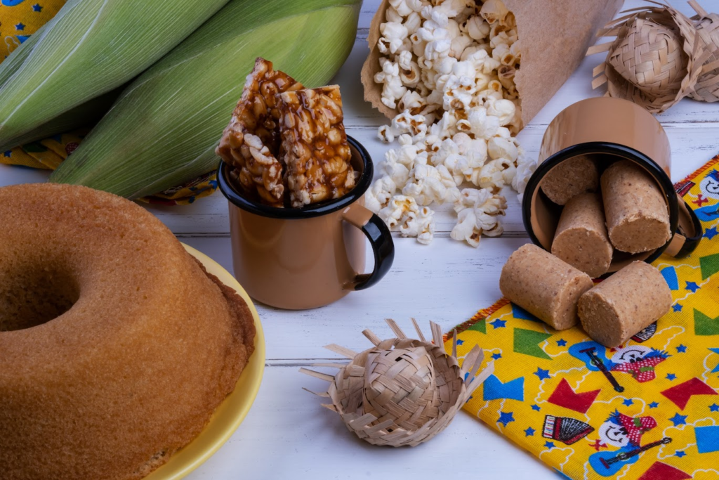 A imagem ilustra o que tem na festa junina: uma mesa com bolo, pé-de-moleque e paçoquinha.