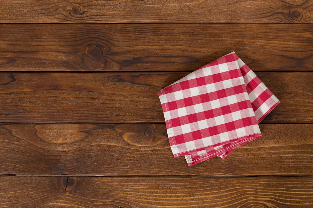 A imagem ilustra uma toalha xadrez vermelha e branca dobrada para o look de inverno da casa.