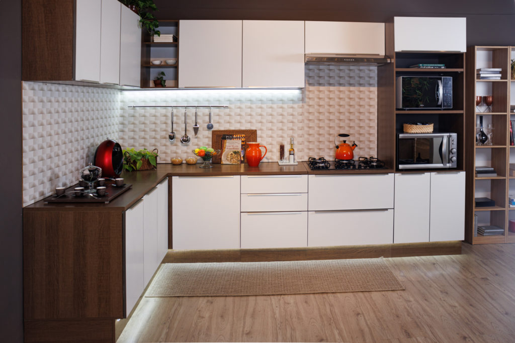 A imagem ilustra uma cozinha branca com madeira Madesa com detalhes em decoração e iluminação.