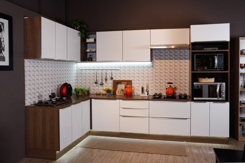 A imagem ilustra uma cozinha branca com madeira Madesa com detalhes em decoração e iluminação.