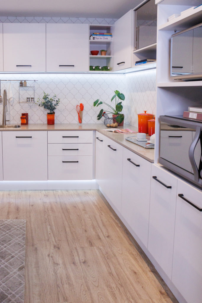 A imagem ilustra o canto de uma cozinha planejada em L, composto por plantas e eletrodomésticos coloridos.
