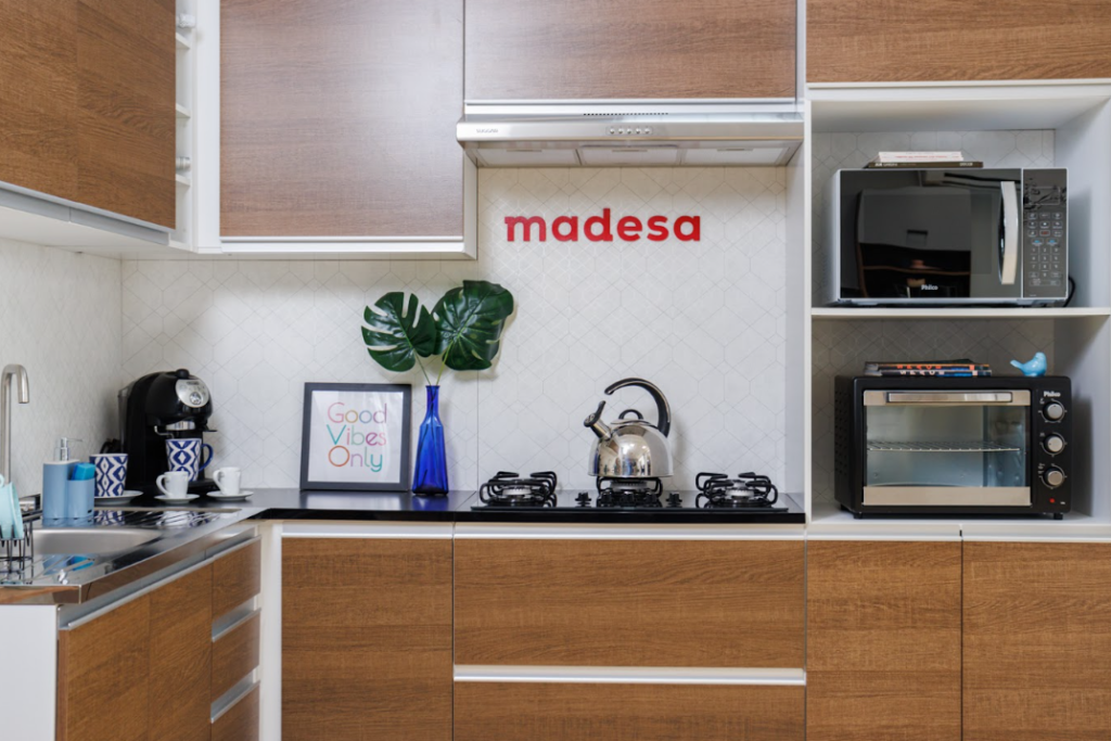 A imagem ilustra um dos modelos de cozinhas Madesa, com acabamento em madeira rústica e pintura branca.