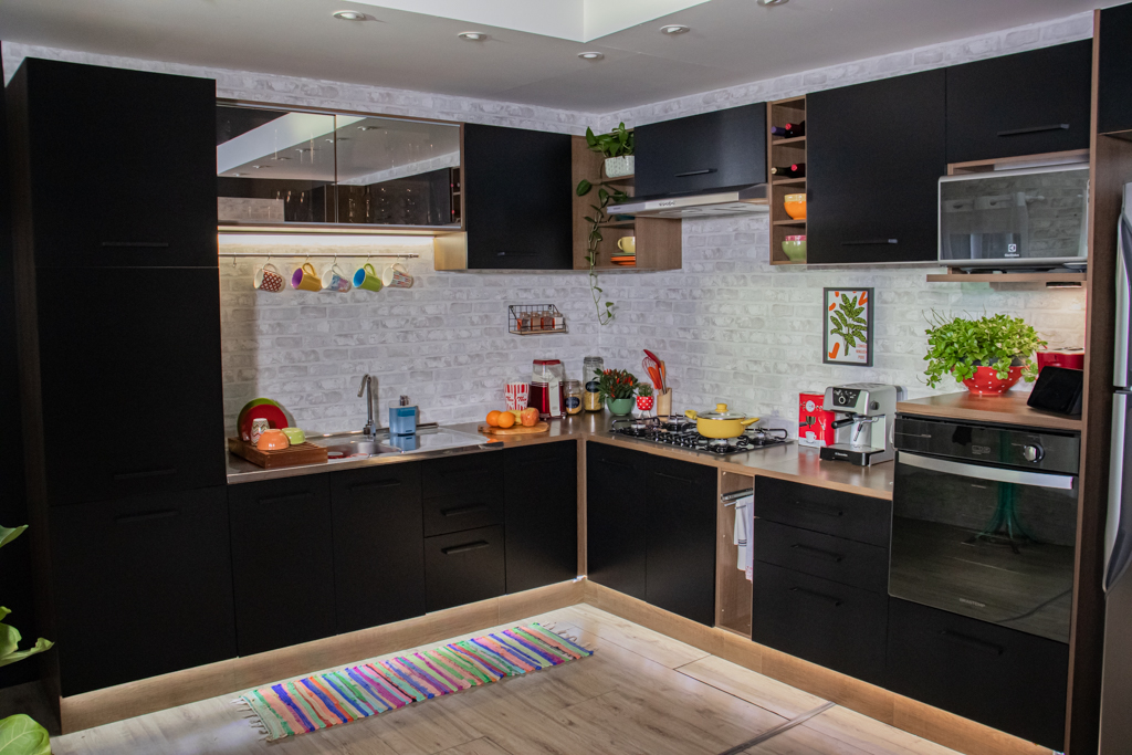 A imagem ilustra uma cozinha planejada Madesa em formato de L na cor preta com detalhes metalizados.
