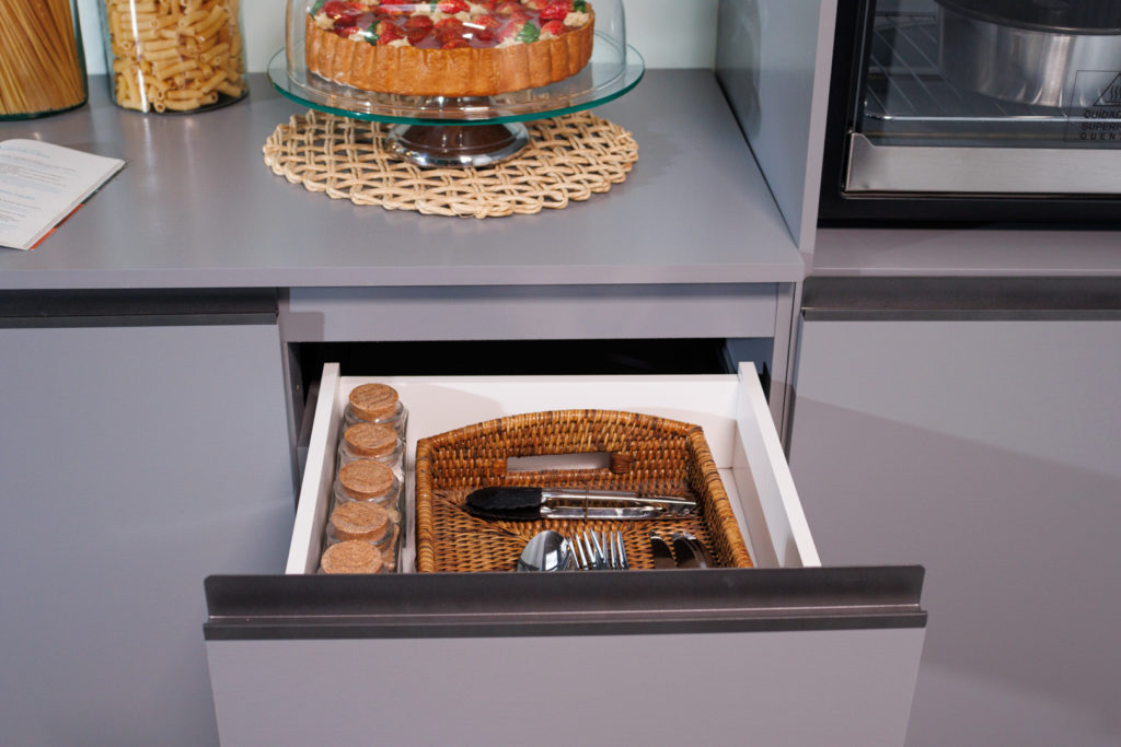 A imagem ilustra uma gaveta de cozinha planejada aberta com utensílios de cozinha dentro.