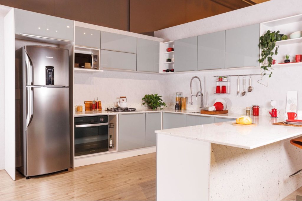 A imagem ilustra uma cozinha planejada na cor cinza com uma pedra para bancada de cozinha na cor branca.