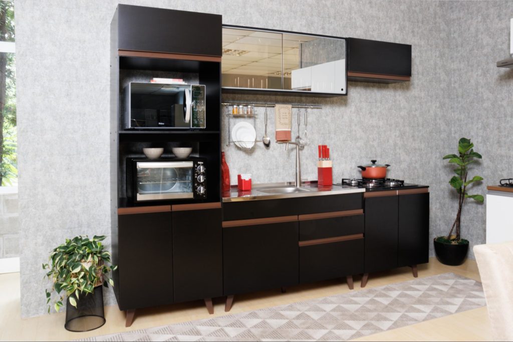 A imagem ilustra uma cozinha planejada compacta com balcões e armários na cor preta. Seus eletrodomésticos estão expostos.