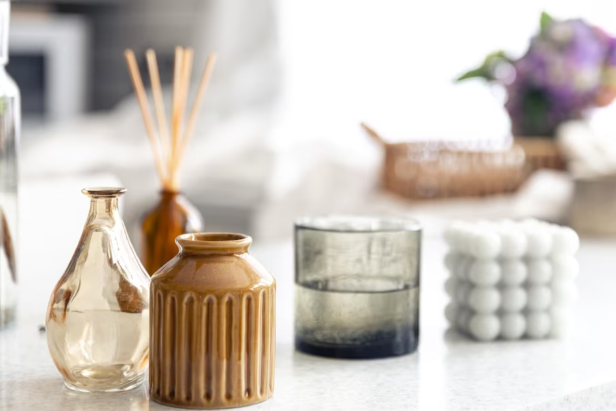 A imagem ilustra o que é aromaterapia em um banheiro através de itens decorativos e um frasco de essência sobre uma superfície branca.