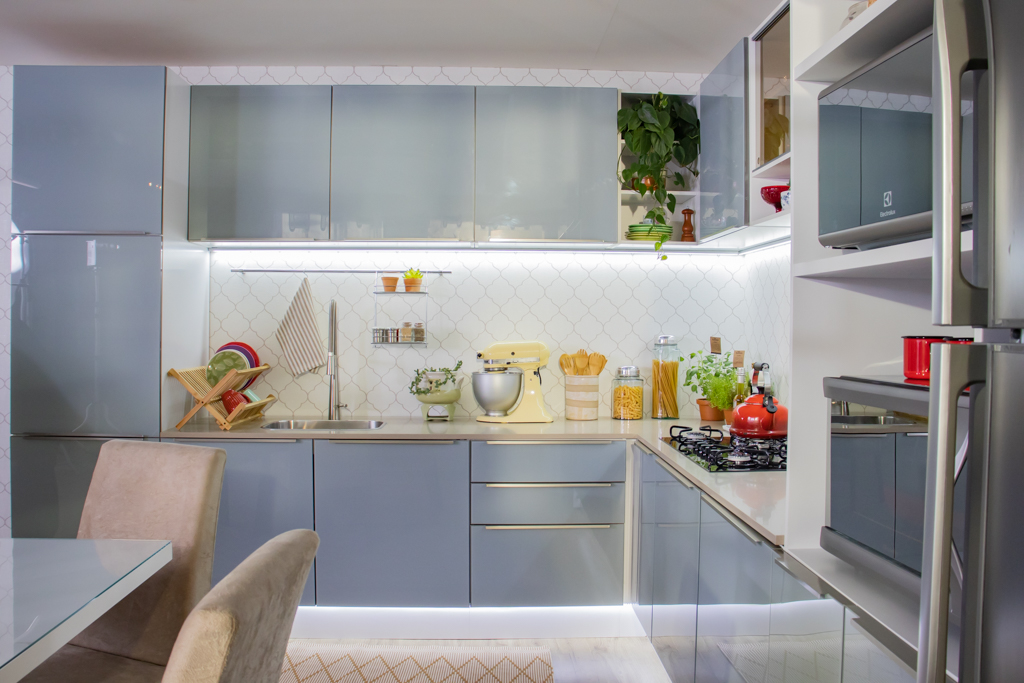 Foto aberta da cozinha Madesa da linha Lux, decorada e com pontos de luz nos armários, na cor cinza.