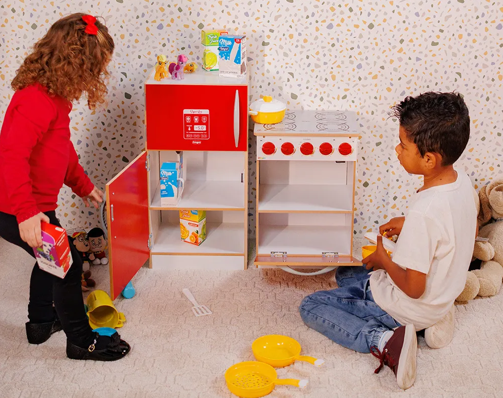 A imagem ilustra duas crianças brincando com a cozinha infantil de madeira Madesa.