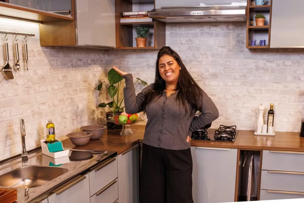 Influenciadora Ailana Nascimento, sorrindo, em frente a uma cozinha Madesa.