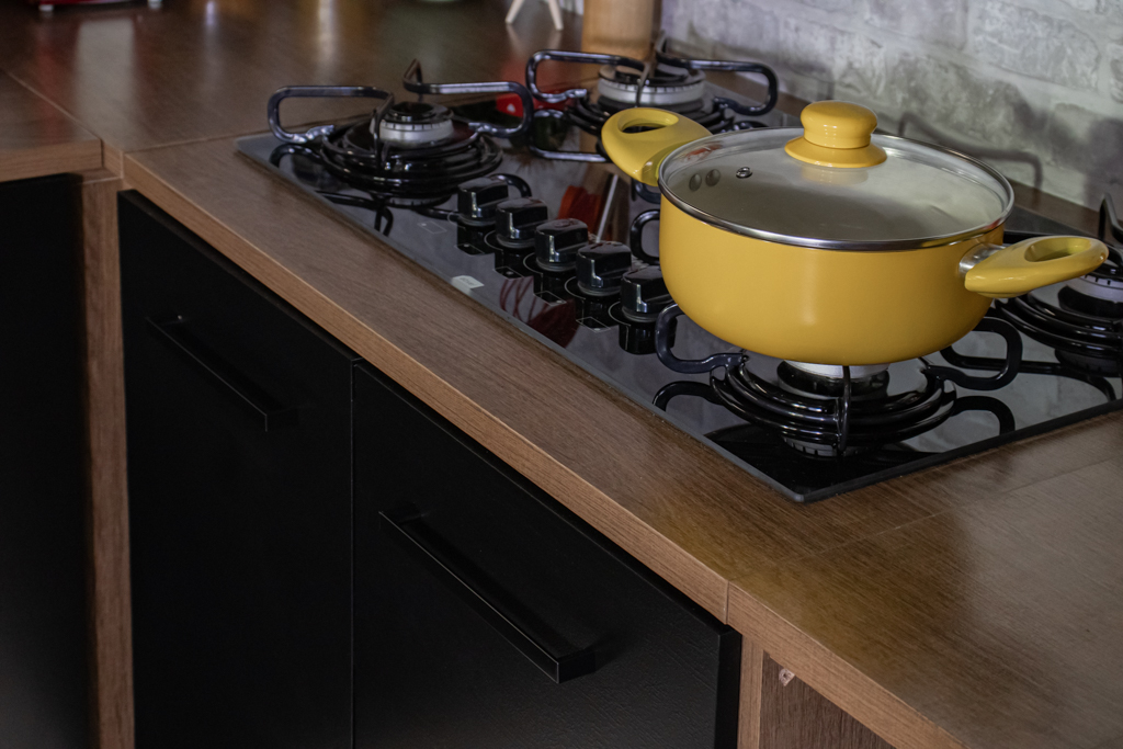 Balcão da cozinha Agata com cooktop instalado, nas cores preto e amadeirado escuro.