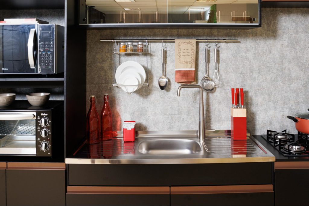 Foto fechada da cozinha completa Reims, na cor preta, decorada com utensílios e eletrodomésticos.