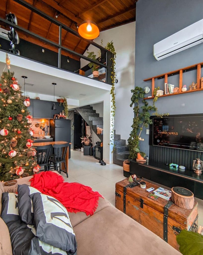 Sala de estar rústica decorada com itens de madeira e árvore de Natal grande à esquerda.