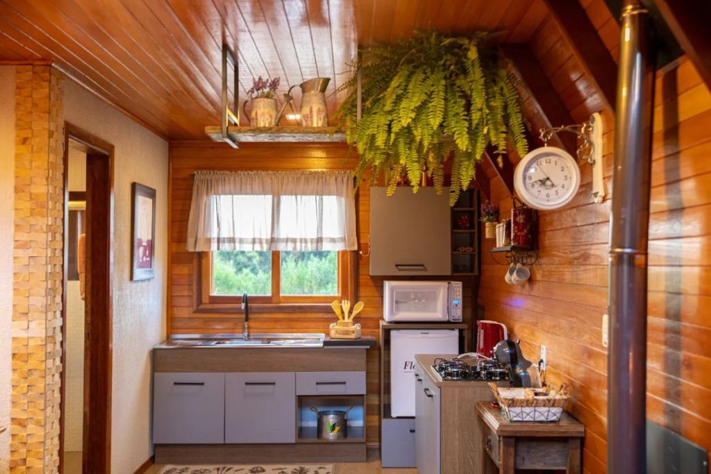 Cozinha Madesa, nas cores rustic e cinza, numa cabana rústica, com foco nos detalhes da decoração, como louças, tapete, e relógio vintage.