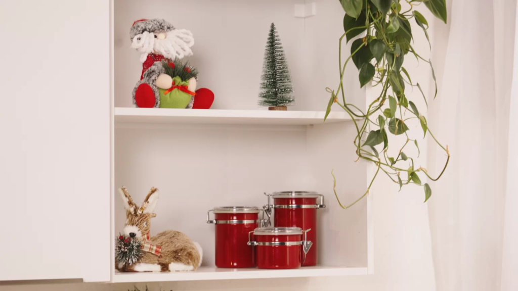 Nicho de cozinha decorado com mini enfeites de Papai Noel, panelas vermelhas e mini árvores de Natal.