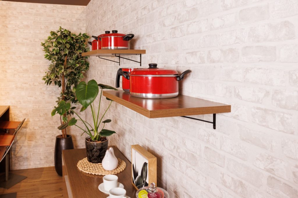 Foto de prateleiras de cozinha, na cor rustic, acima de um balcão de cozinha também decorado com plantas e louças.