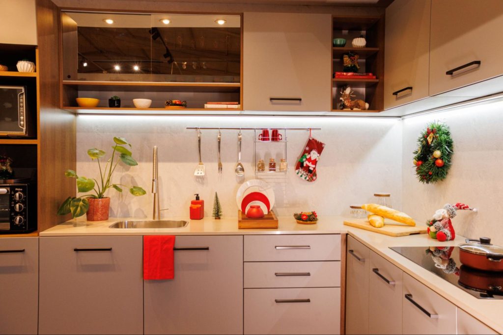 Cozinha Madesa nas cores branco e cinza, decorada com diversos itens natalinos na cor vermelha, utensílios e eletrodomésticos.