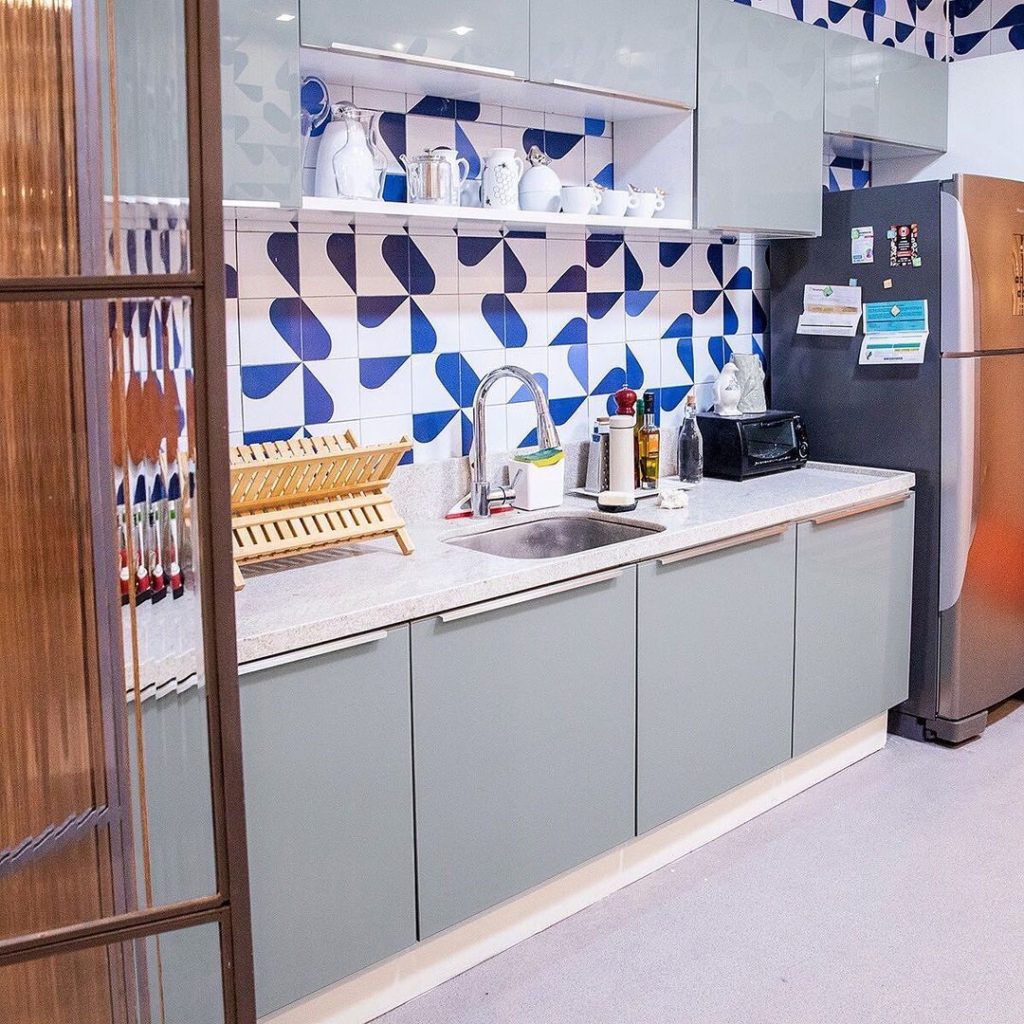 Cozinha Lux Madesa, na cor cinza, decorada com utensílios e eletrodomésticos. A parede ao fundo possui uma estampa azul chamativa.