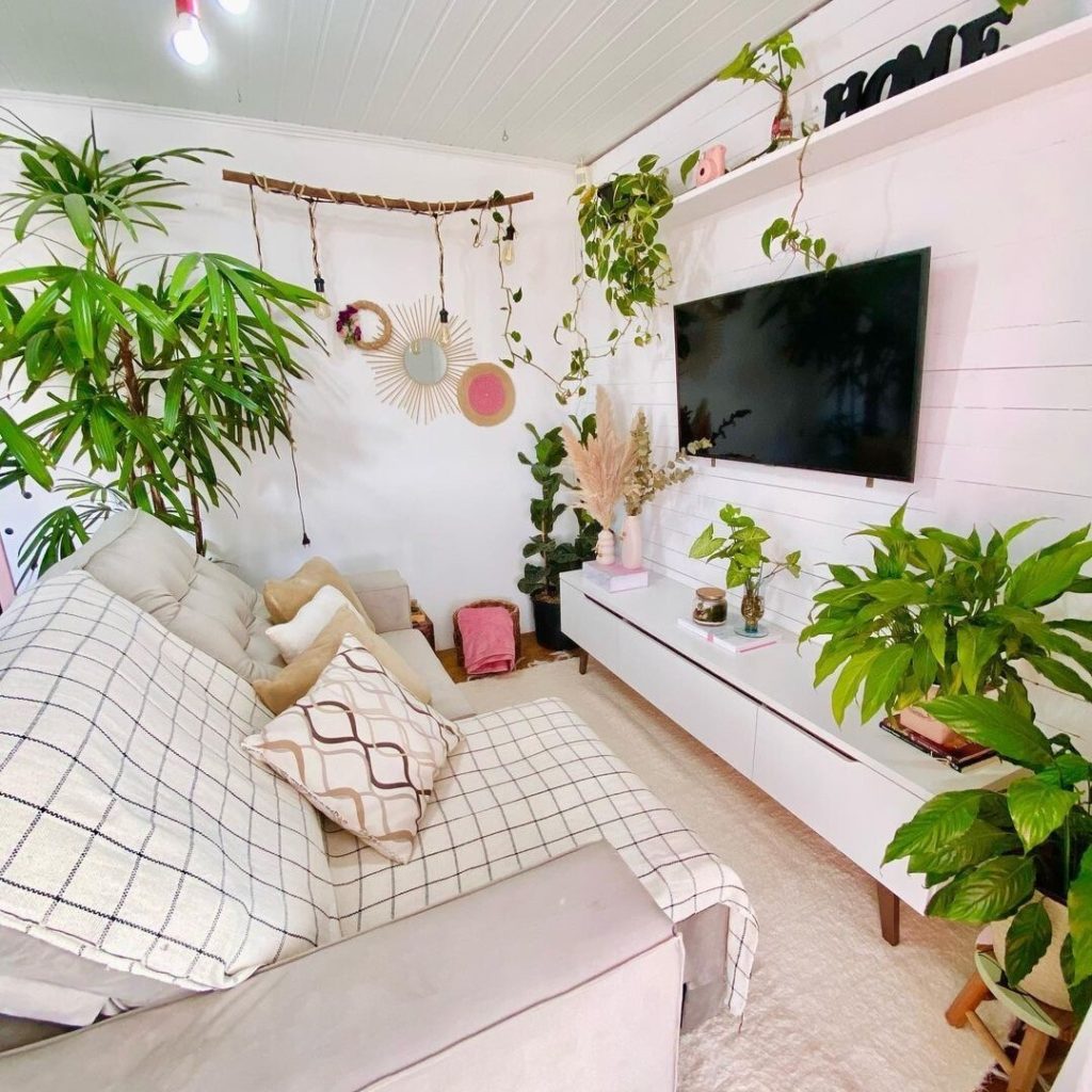 Sala de estar com rack Madesa, decorada com diversas plantas, tecidos estampados no sofá e decorações naturais.