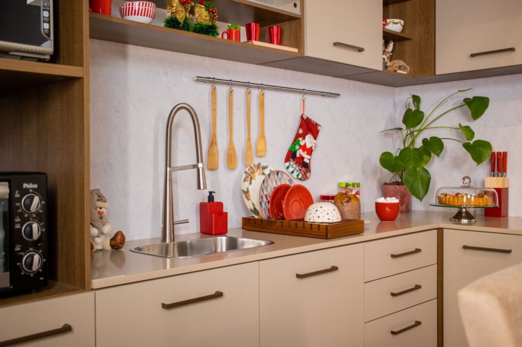 Balcão e pia de cozinha Madesa, decorados com louças vermelhas e utensílios de cozinha temáticos, como colheres de pau e luvas natalinas pendurados.