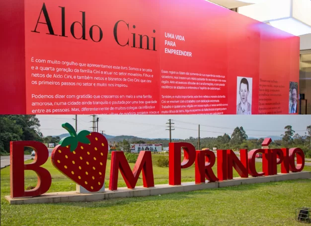 Na parte de cima da imagem, um painel vermelho com a história de Aldo Cini, fundador da Madesa. Logo abaixo, o letreiro da cidade de Bom Princípio.